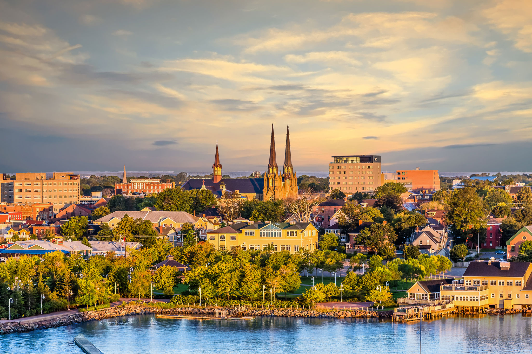 Afternoon sunset washes the bayside city of Charlottetown, a skyline filled with Victorian townhomes, multistoried business buildings, and gothic-style cathedrals.