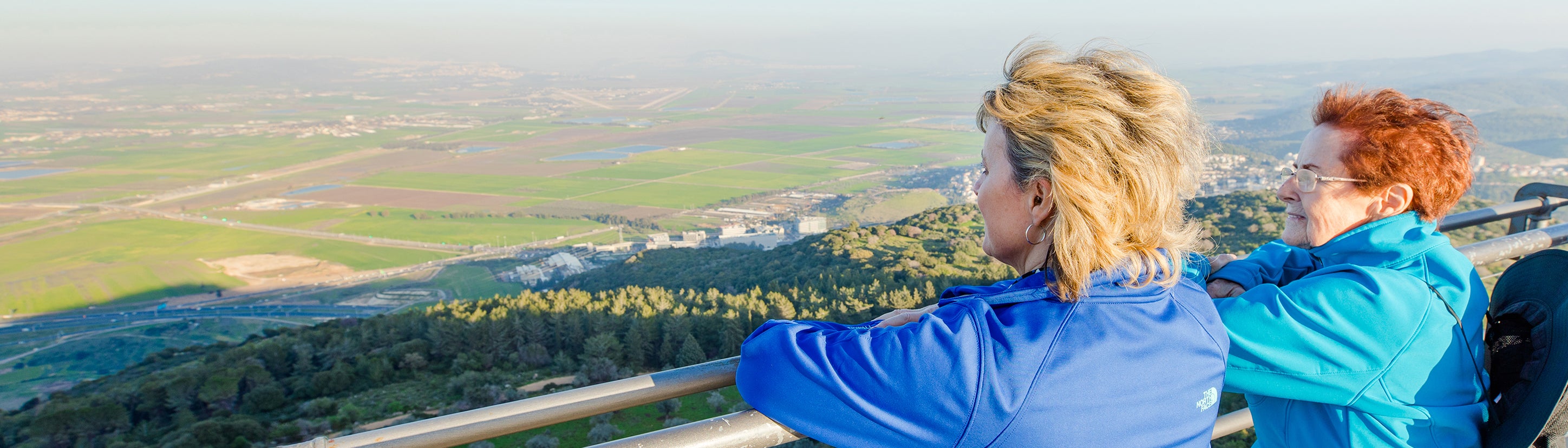 Two travelers looking out over a green valley in Israel