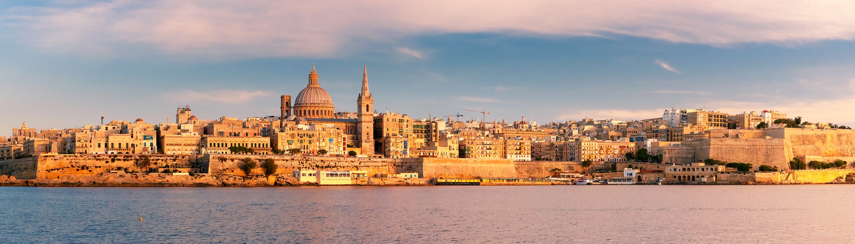 Valletta, Malta waterfront skyline at golden hour, viewed from the harbor