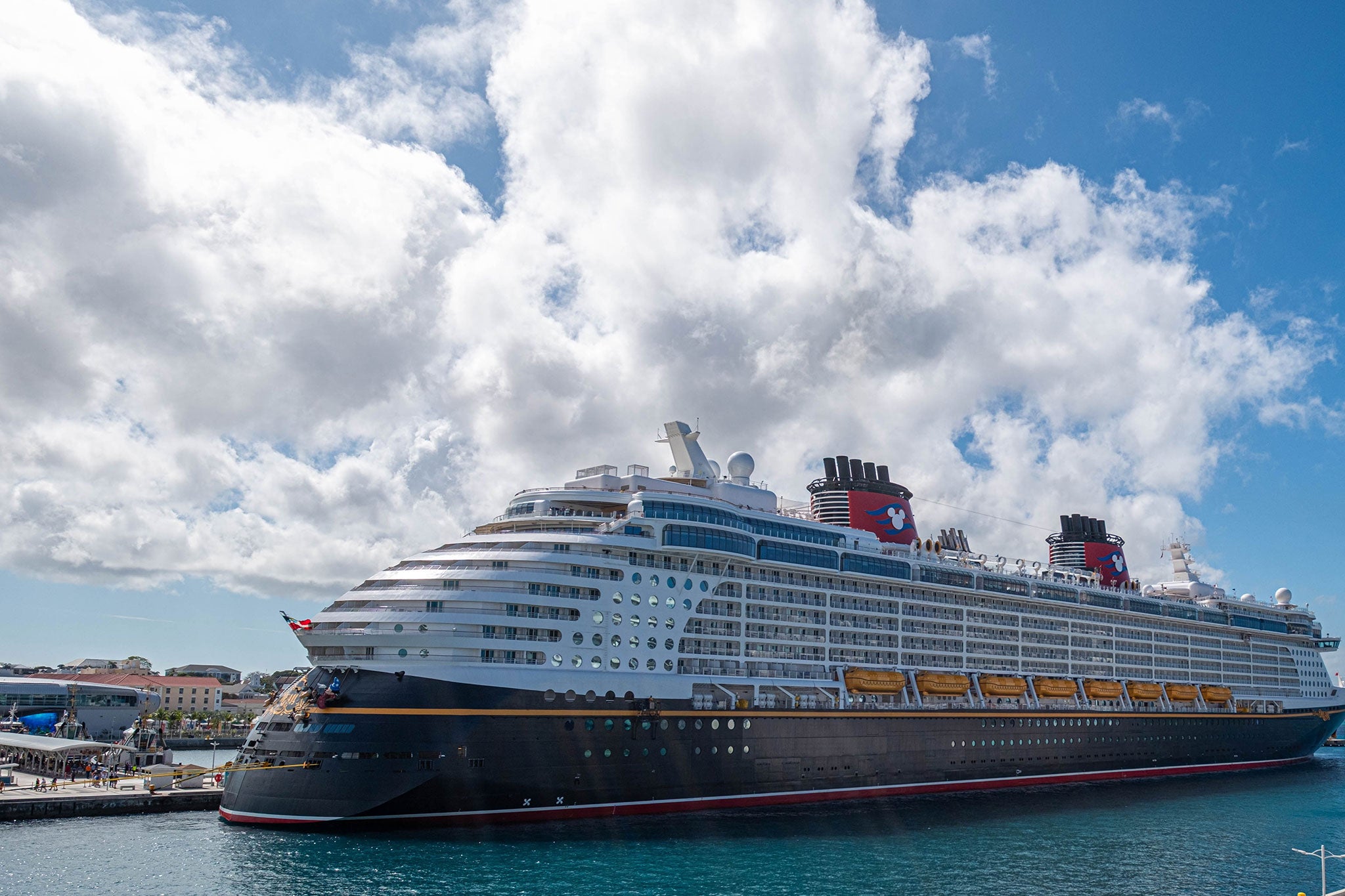  Large luxury cruise ship docked at port on a sunny day with clouds.
