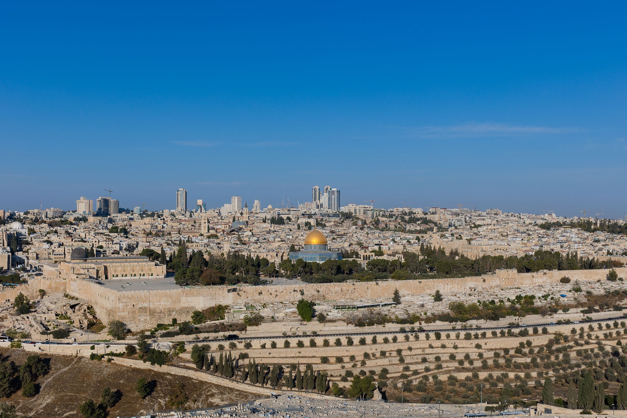 Panoramic view of Jerusalem’s Old City with the Dome of the Rock and ancient stone walls under a clear blue sky.