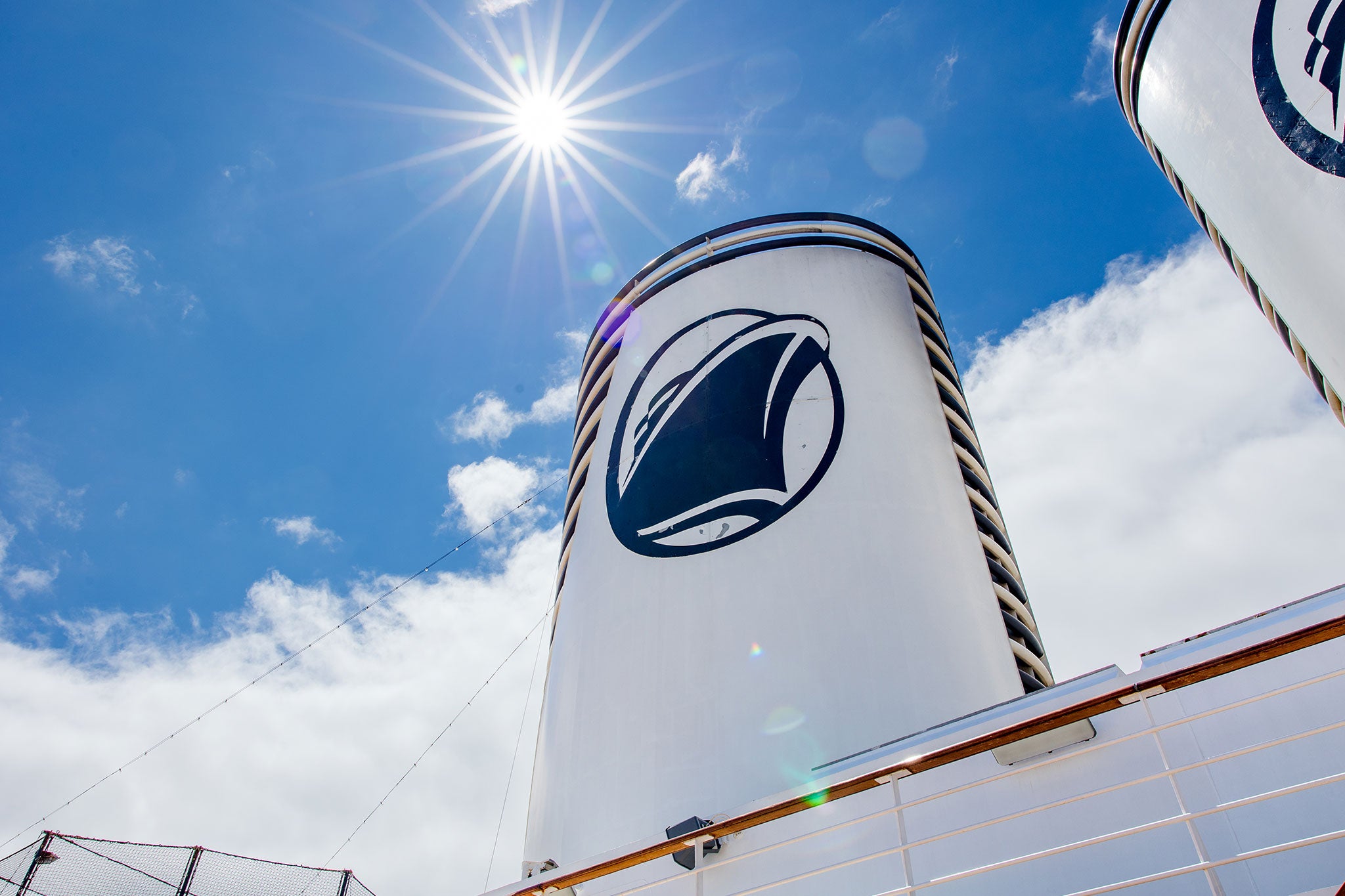 Sunlit cruise ship funnel with Holland America Line logo against blue sky