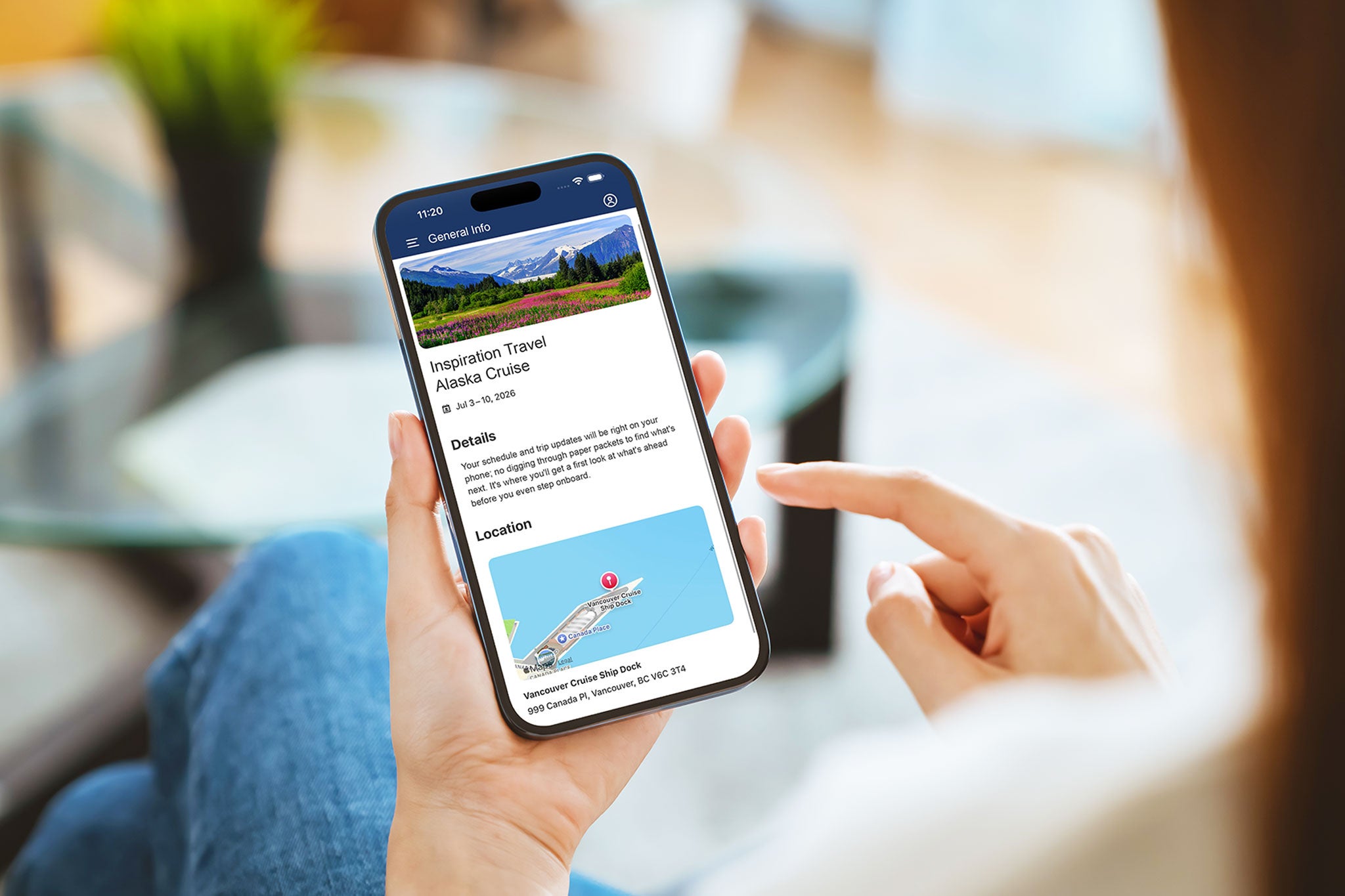 Person on a couch holding a smartphone, viewing information about their Alaska cruise.