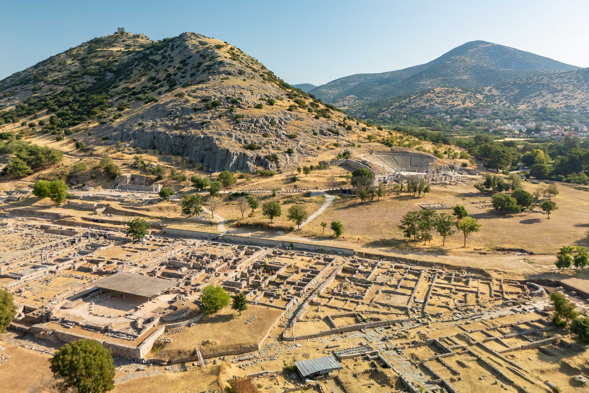 Aerial photo of ancient stone ruins in a dry valley, with mountains in the background.