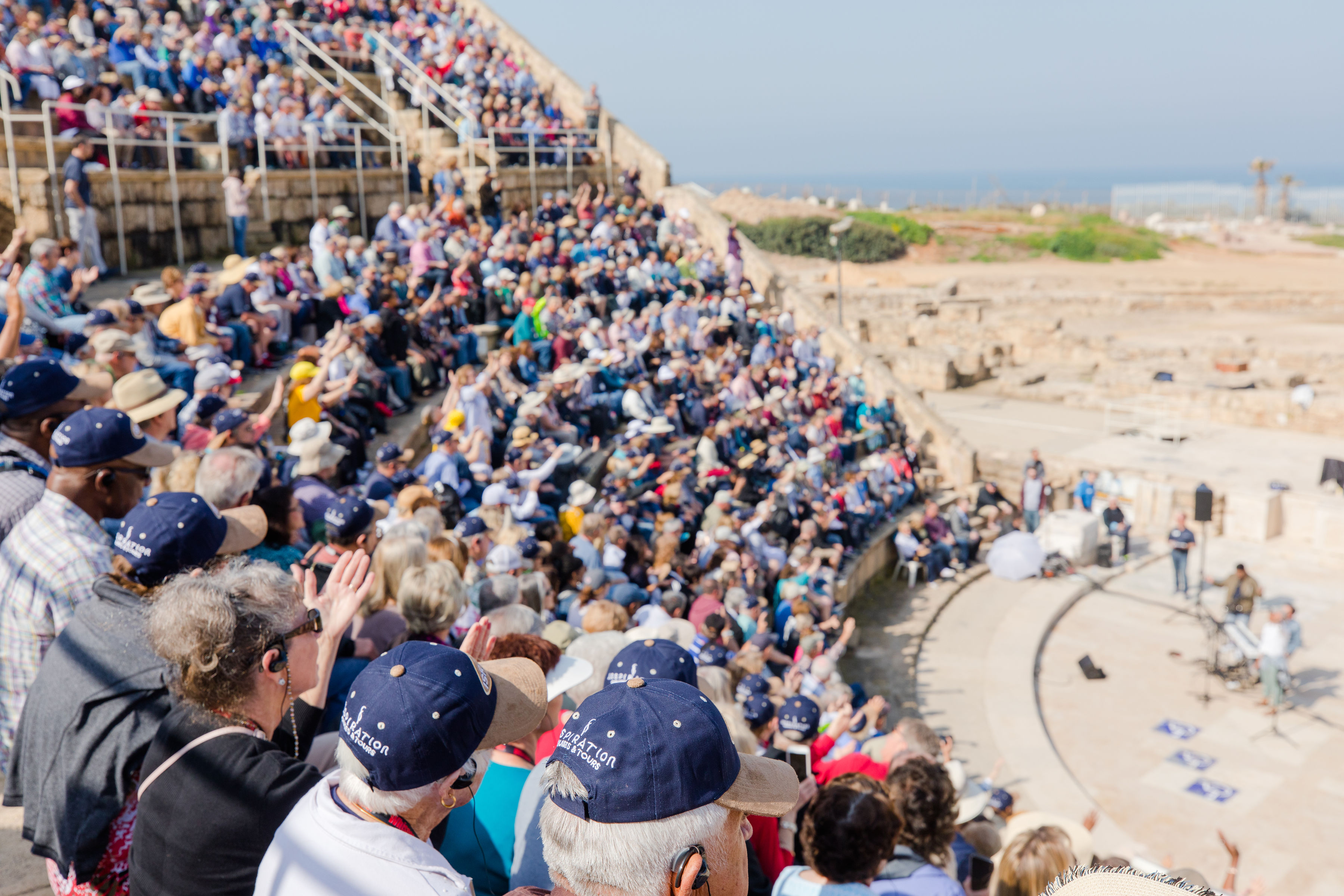 Large group worshiping and praying in the Roman Amphitheater at Caesarea Maritima.
