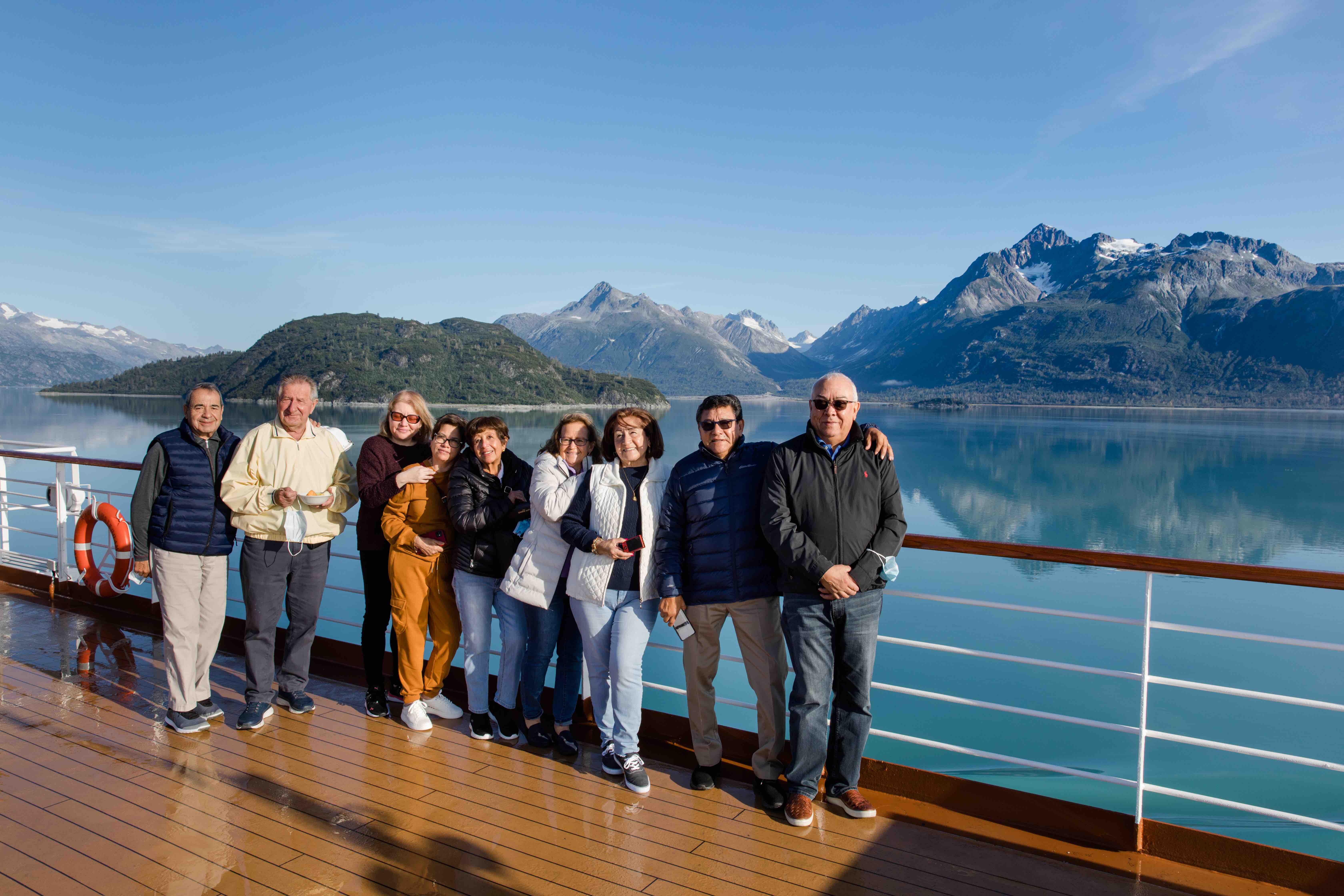 A group of travelers posing for a picture on the deck of a cruise ship