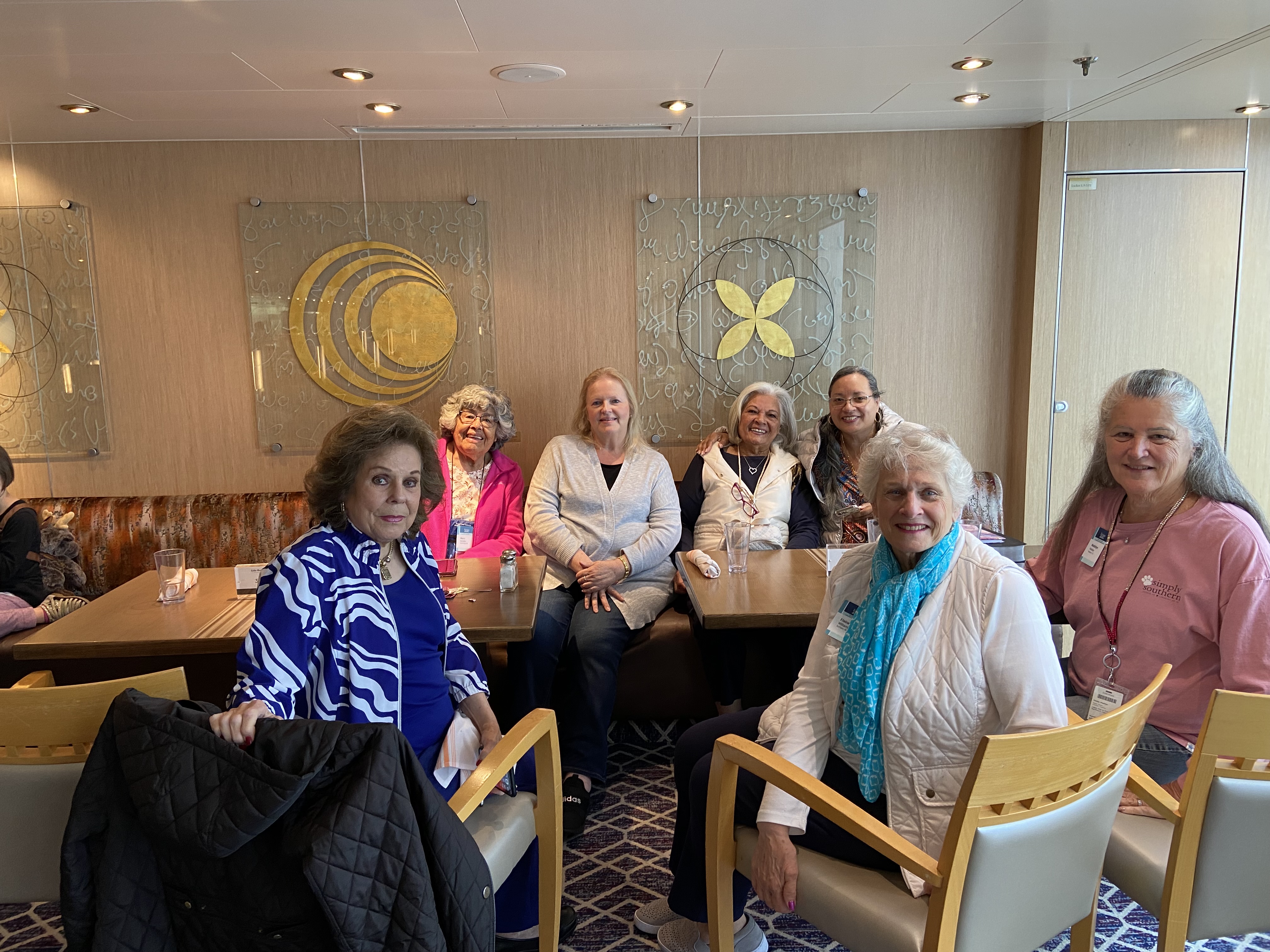 A group of ladies sitting at a cruise table smiling for the camera