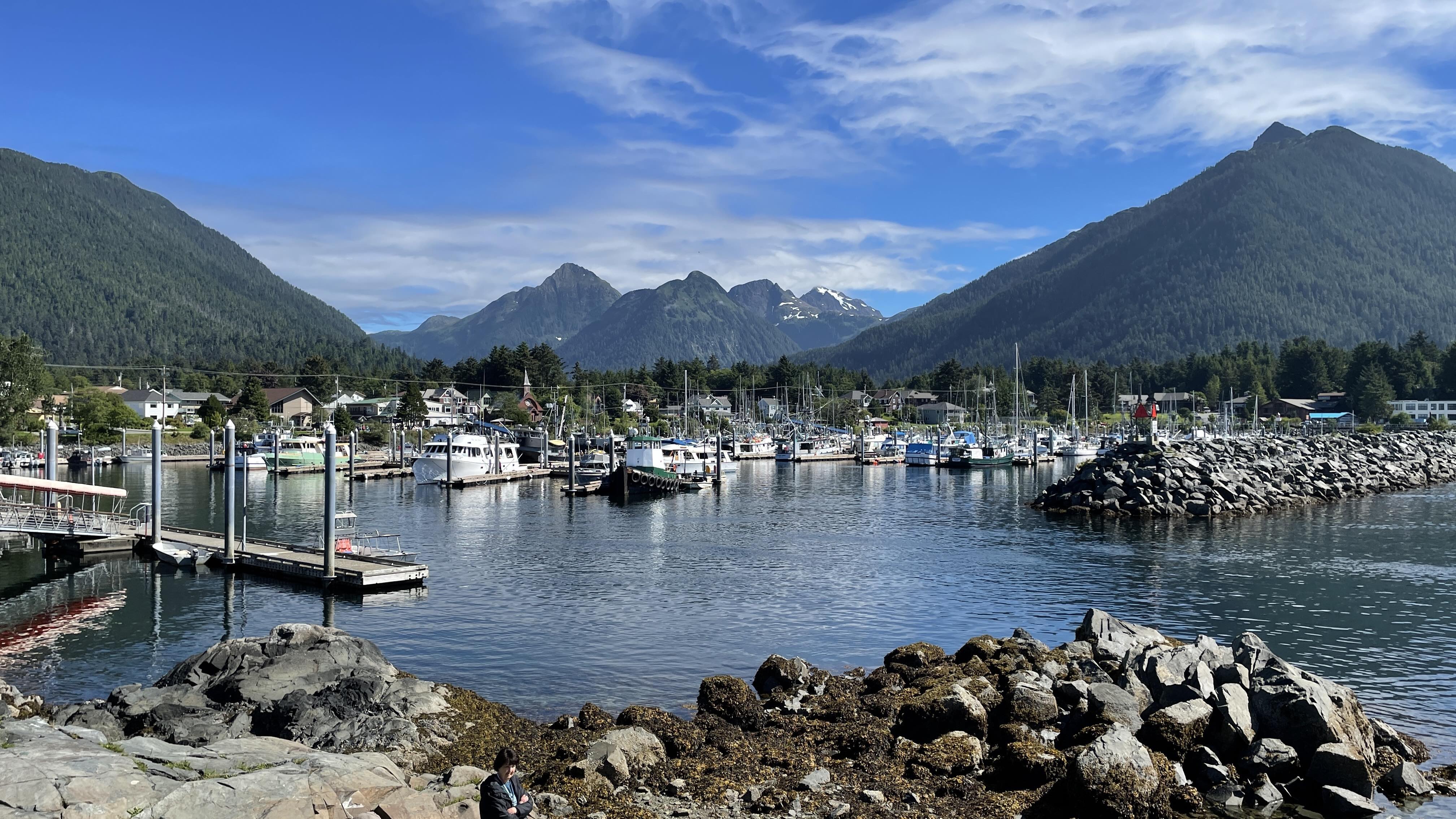 Boats docked at a rocky port with majestic mountains of Alaska in the background