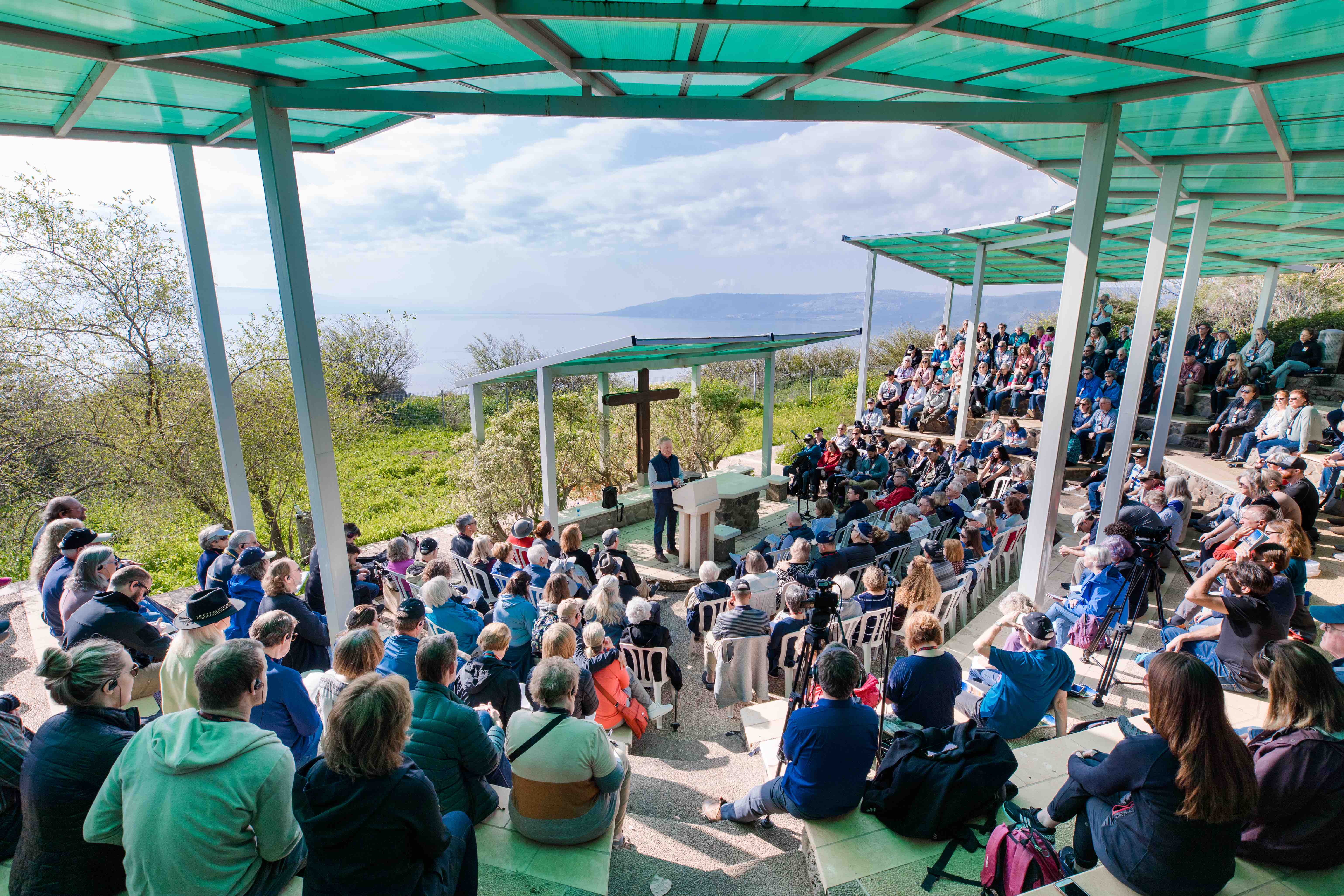 Travelers listen to Max Lucado preach overlooking the Sea of Galilee
