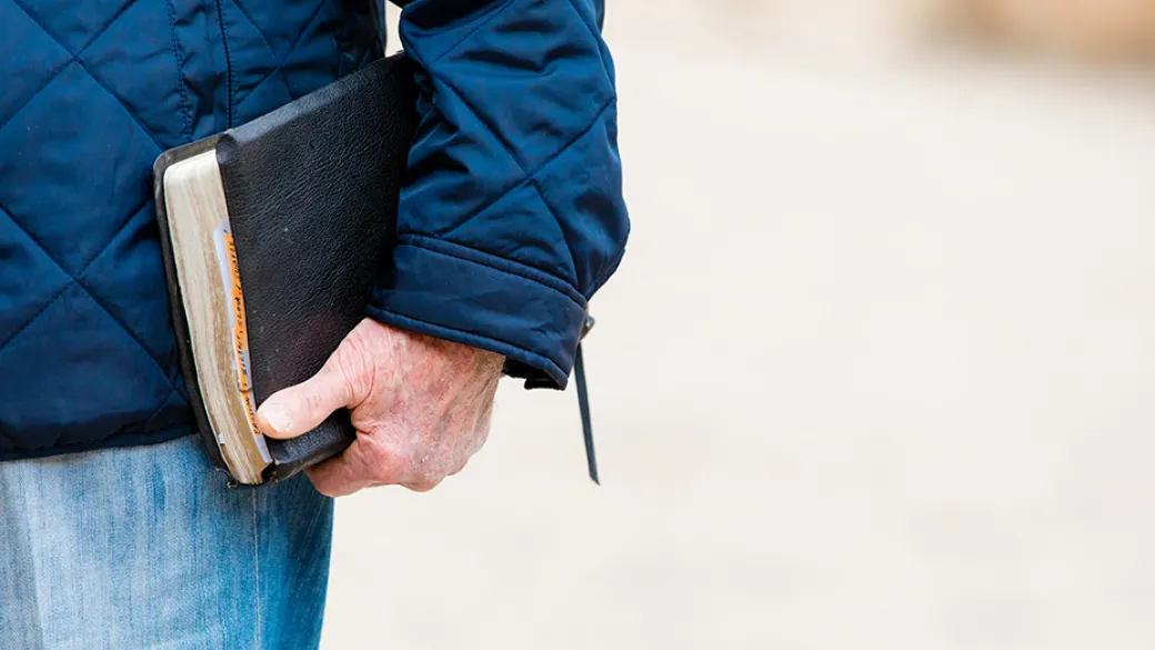 man's hand holding bible