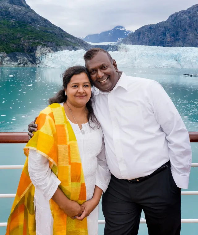 Smiling couple standing close together with icy glacier in the background