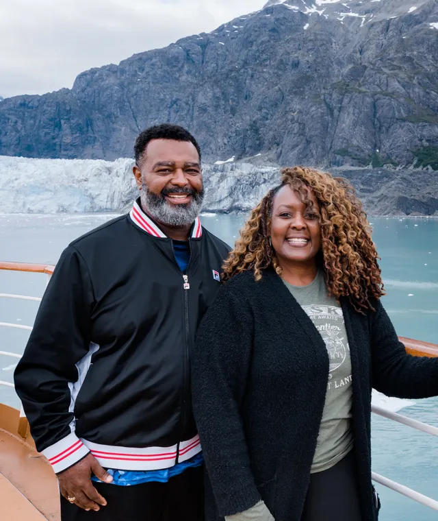 Smiling couple standing close together with icy glacier in the background