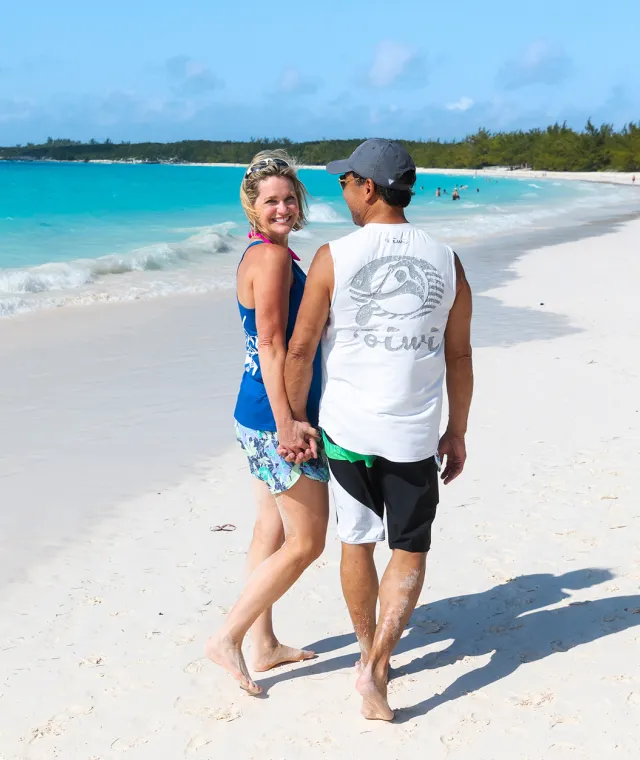 A couple holding hands and walking along the beach