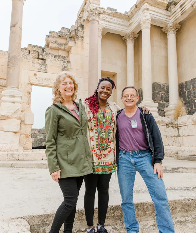 Smiling travelers standing amid ancient ruins