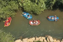 Overhead aerial view of kayaks floating in a river surrounded by trees and rocks