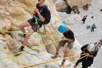 Participants rappelling down the limestone cliffs of Nahal Tamar near the Dead Sea, wearing helmets and harnesses during a guided desert adventure.