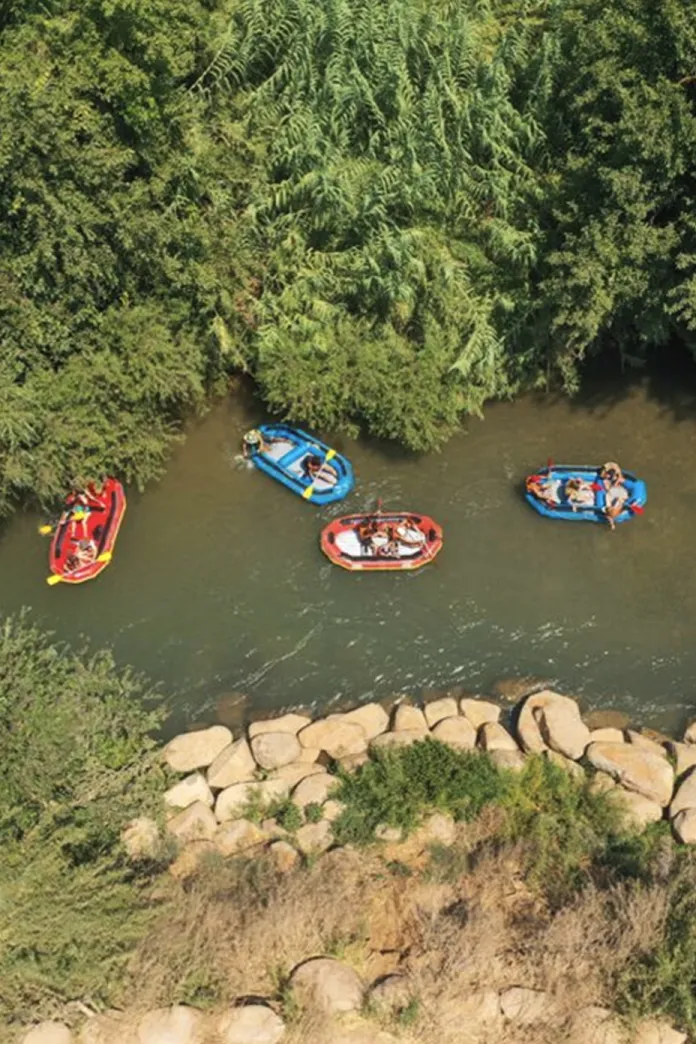 Overhead aerial view of kayaks floating in a river surrounded by trees and rocks