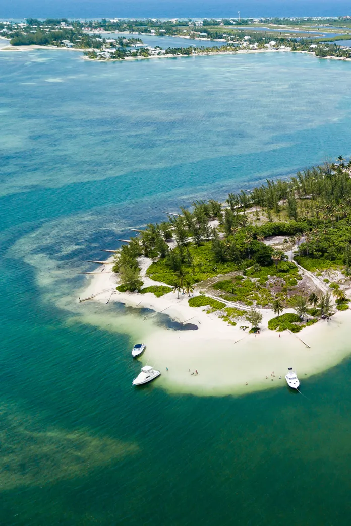 Aerial view of a sandy island tip with turquoise waters and anchored boats, Cayman Islands