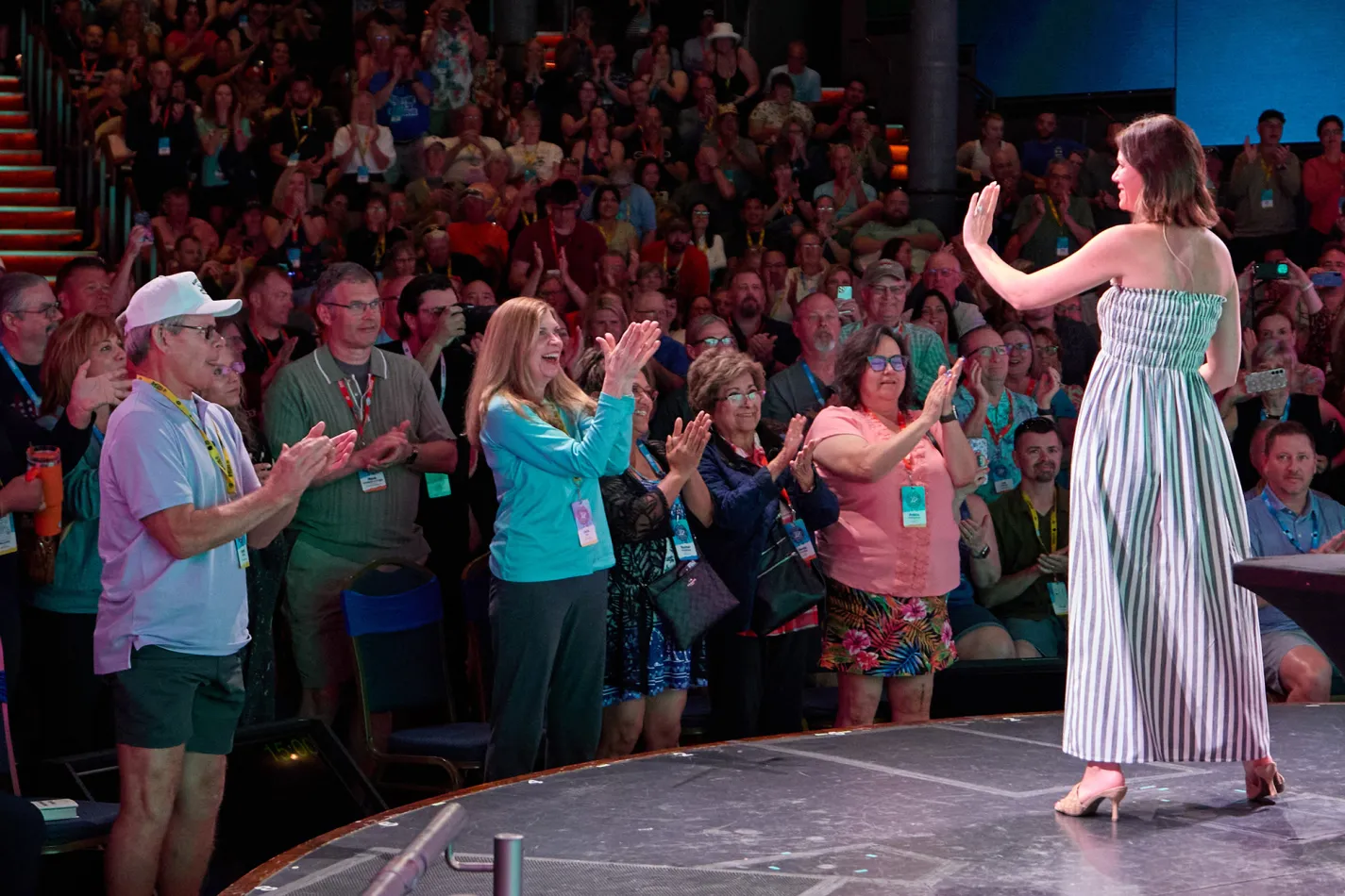 Woman on a stage smiling and speaking to a cheering crowd