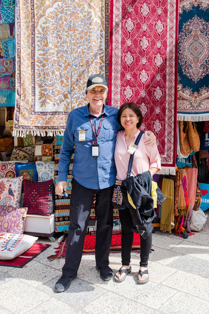 Smiling couple standing in front of colorful hanging carpets and pillows