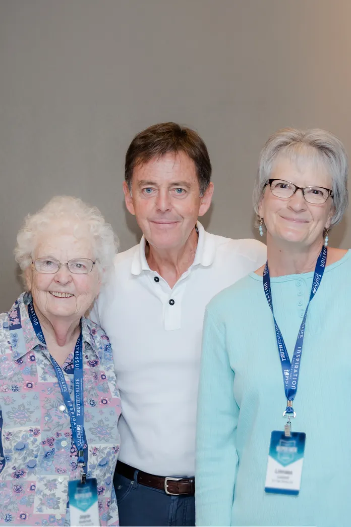 Alistair Begg standing with two travelers