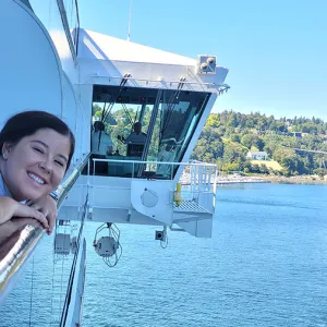Smiling woman leaning over the deck of a cruise ship