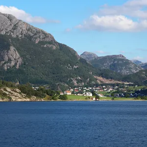 A town nestled in a valley surrounded by large mountains and water