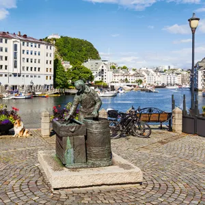 A metal statue with a river and buildings in the background