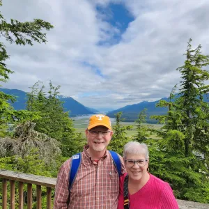 A senior couple, smiling with the mountains in the background