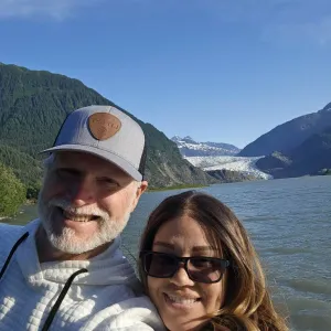 Smiling couple taking a selfie with the water and mountains in the background