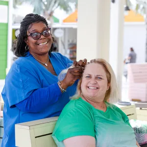 A woman braid another woman's hair