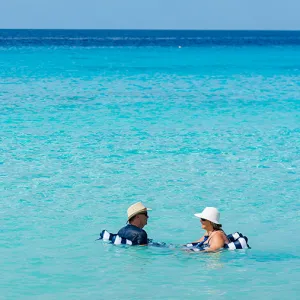 Two people swimming in the turquoise blue ocean water