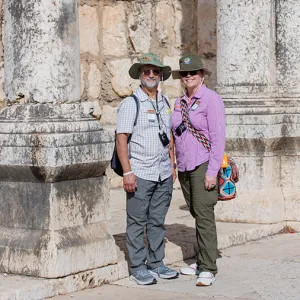 Smiling couple standing in front of an ancient stone structure