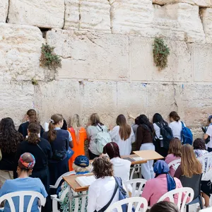 Travelers sitting and standing at the Western Wall in Israel